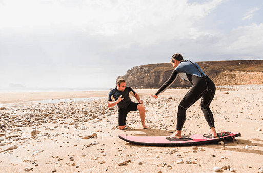 Kumun üzerinde erken eğitimenden surf dersi alan erkek öğrenci.